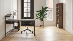 an empty room with a desk, chair and potted plant in the corner on wheels