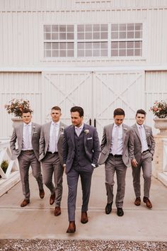 a group of men standing next to each other in front of a white barn door