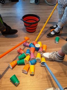 several people are standing around with cups and brooms on the floor