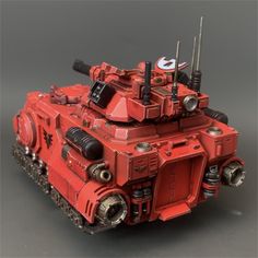 a red and black toy tank sitting on top of a table