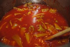 a pot filled with pasta and sauce on top of a wooden spoon in the middle of it