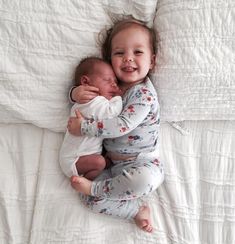 two babies cuddle together on a bed