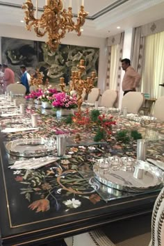 a dining room table is set with place settings and flowers in vases on it