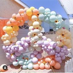 a bunch of balloons that are hanging from the side of a building with flowers on them