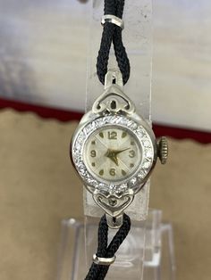 "Vintage Custom Swiss Watch made with Heart Lugs in Solid 14 Karat White Gold Art Deco Style with 20 1 Point Diamond Surround Bezel (0.20 Ct) Black Silk Cord Strap 6.75 Inch in length White Gold Filled Clasp. The Case is 5/8 inch diameter with Yellow Gold Numerals and Hands New Crystal Made in the late 1930's early 1940's this is a Mechanical Hand Wind Swiss 21 Jewel Movement Runs Beautiful one of a kind Watch 2859 Back has \"J14KaratJ\" 8/10/2020 gold $2028 Free priority Mail Shipping in USA" Black Diamond Evening Watch, Diamond White Watch With Rhinestones For Formal Occasions, Diamond White Diamond Watch With Rhinestones For Formal Occasions, Formal Diamond White Watch With Rhinestones, Formal Black Diamond Watch With Diamond Accents, Elegant Round Diamond Watch Band, Black Formal Watches With Diamond Accents, Formal Black Watches With Diamond Accents, Black Watches With Diamond Accents For Formal Occasions