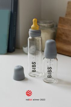 two baby bottles sitting on top of a table next to a bottle with the word boss written on it