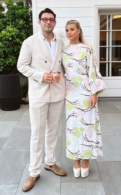 a man and woman standing next to each other in front of a building with plants