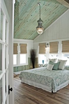 a bedroom with wooden floors and white walls, has a large bed in the center