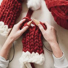 someone is knitting a red and white knitted scarf with a santa hat on top