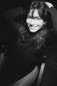 a black and white photo of a woman with her hair in the air, smiling