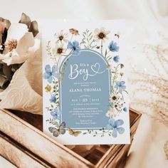 a blue and white floral baby shower is in a wooden box next to some flowers