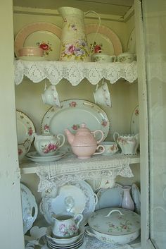 an old china cabinet filled with dishes and other vintage items, such as tea cups and saucers