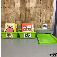 three green trays with matching books on them sitting on a counter next to a wooden wall