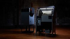 two black and white machines sitting on top of a hard wood floor in the dark