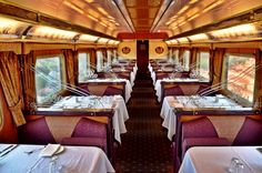 the interior of a train car with tables and chairs set up for formal dining in it