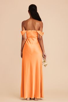 a woman in an orange dress with her back to the camera, looking at something