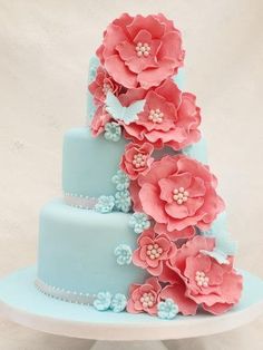 a three tiered blue cake with flowers on the top and numbers below it,