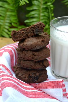 a stack of cookies next to a glass of milk on a red and white towel