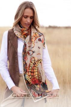 Woman wearing a colorful patterned scarf with wildlife motifs, standing in a grassy field.