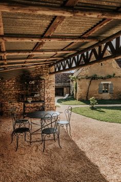 an outdoor patio with tables and chairs under a wooden roof over looking a courtyard area