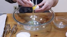 a man mixing ingredients in a bowl on top of a wooden table