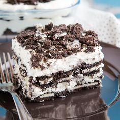 a piece of ice cream cake on a plate with a fork and glass bowl in the background