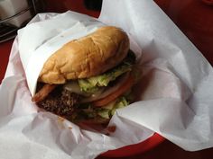 a hamburger with lettuce, tomato and other toppings in a paper wrapper