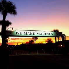 we make marines sign in front of palm trees at sunset with the sun setting behind it