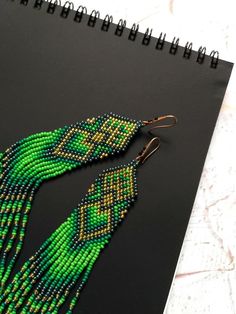 Elegant long green earrings. Unique seed bead earrings. | Etsy Green Dangle Beaded Earrings With Gold Beads, Traditional Green Beaded Dangle Earrings, Bohemian Green Earrings With Gold Beads, Green Colorful Dangle Jewelry, Green Dangle Jewelry With Colorful Beads, Green Gold Beaded Drop Earrings, Green Drop Earrings With Gold Beads, Traditional Green Beaded Earrings With Tiny Beads, Green Beaded Bohemian Chandelier Earrings