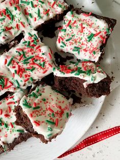 a plate full of brownies with white frosting and sprinkles