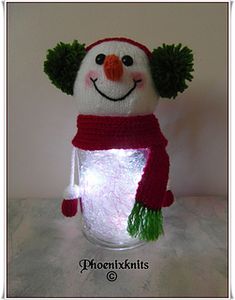 a knitted snowman with a red hat, scarf and green pom - poms