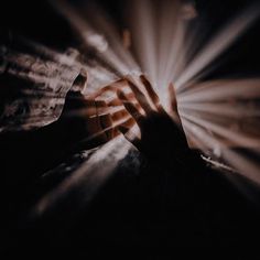 two hands reaching towards each other with light coming from behind them on a dark background