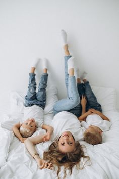 two people laying on a bed with white sheets