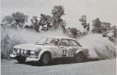 an old race car driving down a dirt road with dust coming out of the tires