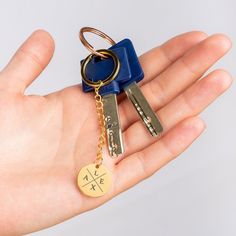 a person holding two keys in their hand with the keychain attached to them