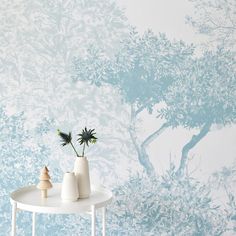 two vases with flowers on a table in front of a wallpapered background