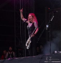 a woman standing on top of a stage holding a guitar