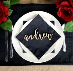 a black and white place setting with red roses