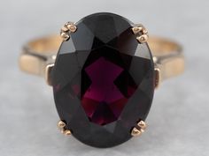 "Always popular and never out of style, this vintage ring is a modestly sized cocktail piece that is easy to wear day or evening! The center stone is a bright grape garnet with sumptuous flashes of violet, cabernet, and berry pink. The airy design of the undercarriage lets plenty of light flow through the stone! Metal: 14K Yellow Gold Gem: Grape Garnet 7.11 Carats Gem Measurements: 10.5 x 14.4 mm, Oval Ring Size: 7.50 Marks: \"14K\" Stamped on the inside band SKU #: 005P394A Each piece has been Purple Ruby Ring For Formal Occasions, Formal Garnet Burgundy Ring, Formal Burgundy Garnet Ring, Formal Purple Ruby Ring, Formal Purple Ruby Ring With Center Stone, Classic Burgundy Ruby Ring For Formal Occasions, Formal Purple Oval Ruby Ring, Classic Formal Burgundy Rings, Garnet Gold Ring