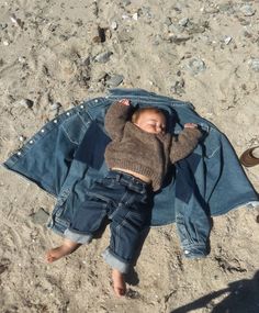 a baby laying on top of a denim jacket