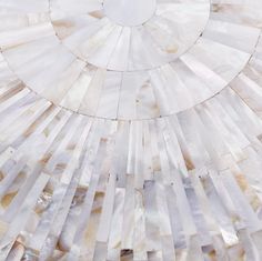 a circular mirror made out of mother of pearl shells on a white background with silver accents