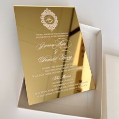 an elegant gold wedding card in a white box