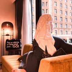 a woman sitting on top of a couch in a living room next to a window