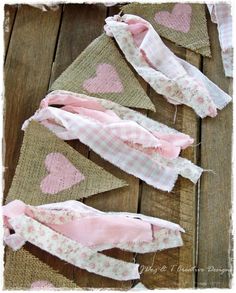 pink and white hearts on burlap hanging from wooden planks, with one folded over the other