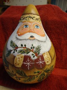 a painted rock with a santa clause on it sitting on a red towel in front of a chair