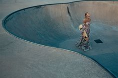 a woman is standing at the top of a skateboard ramp in a dress and hat