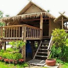 a small hut with steps leading up to it and plants growing around the porch area