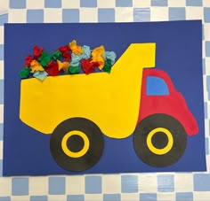 a paper construction truck with gummy bears in the back on a blue and white checkered tablecloth