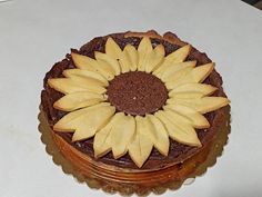 a chocolate cake topped with sliced apples and a sunflower