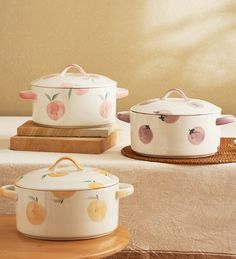 three pots with peaches painted on them sitting on a table next to each other